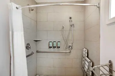 a shower stall in a bathroom withige tiles at Best Western Inn in Merced