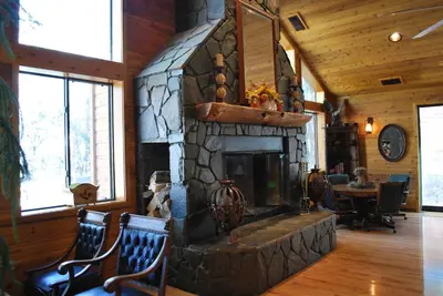 a stone fireplace in a living room with two chairs at Double Eagle Resort and Spa in June Lake