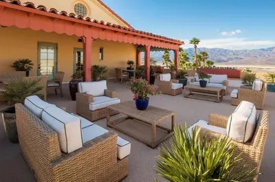 a patio with wicker chairs and tables in front of a house at The Inn at Death Valley in Death Valley