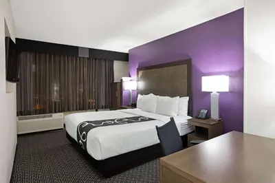 a hotel room with a large bed and purple walls at La Quinta by Wyndham Rancho Cordova Sacramento in Rancho Cordova