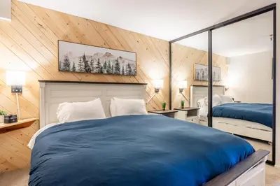 a bedroom with a blue bed and a mirror at Bridges 107 in Mammoth Lakes