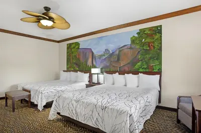 two beds in a room with a painting on the wall at Best Western Plus Yosemite Gateway Inn in Oakhurst
