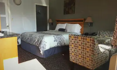 a hotel room with a bed and a chair at Garden View Inn in Fresno