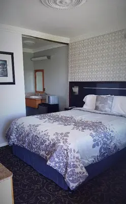 a bedroom with a large bed with a blue and white blanket at Garden View Inn in Fresno