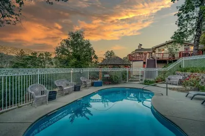 a swimming pool with chairs and a fence at A Bed of Roses in Yosemite Forks
