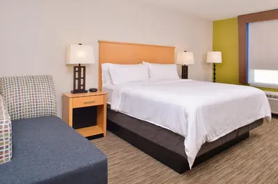 a hotel room with a large bed and a chair at Holiday Inn Express Stockton Southeast by IHG in Stockton