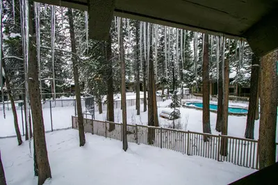 a view of a deck with snow covered trees and a pool at Sunshine Village 104 Condo in Mammoth Lakes