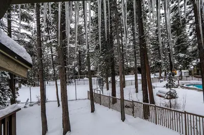 a snow covered yard with a fence and trees at Sunshine Village 104 Condo in Mammoth Lakes