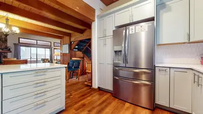a kitchen with white cabinets and a stainless steel refrigerator at Winterset 12 Condo in Mammoth Lakes