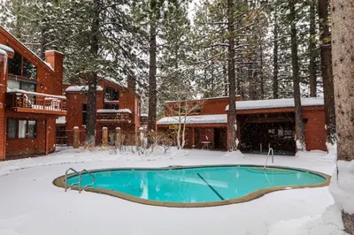 a swimming pool in the snow in front of a house at Woodlands #33 Condo in Mammoth Lakes