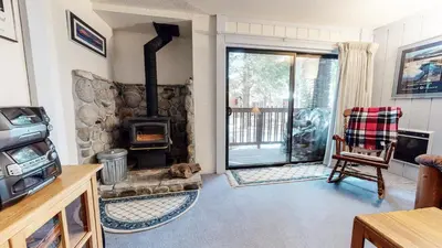 a living room with a stone fireplace and a chair at Summit Condominium #41 Condo in Mammoth Lakes