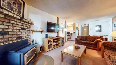 a living room with a fireplace and a couch and a tv at Summit Condominium #267 Condo in Mammoth Lakes