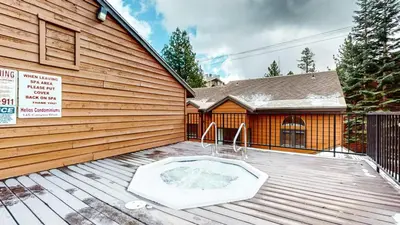 a hot tub on a deck in front of a house at Helios North #5 Condo in Mammoth Lakes