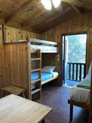 a bedroom with bunk beds in a wooden cabin at Yosemite RV Resort in Coarsegold