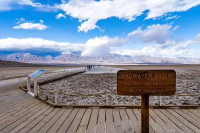 a sign on a beach with mountains in the background at The Ranch At Death Valley in Death Valley