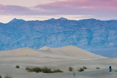 a person standing on a sand dune in front of mountains at The Ranch At Death Valley in Death Valley