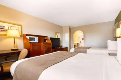 a hotel room with two beds and a desk at Auburn House Hotel in Auburn