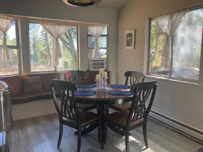 a dining room with a table and chairs and windows at NEW! Cozy & Secluded House w/Deck - Near Yosemite! in Tuolumne