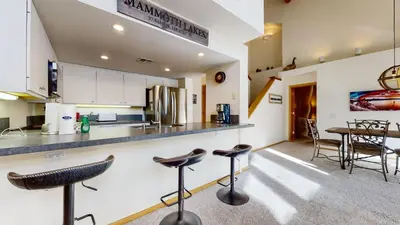 a kitchen with bar stools and a dining room at Snowcreek 880 Condo in Mammoth Lakes
