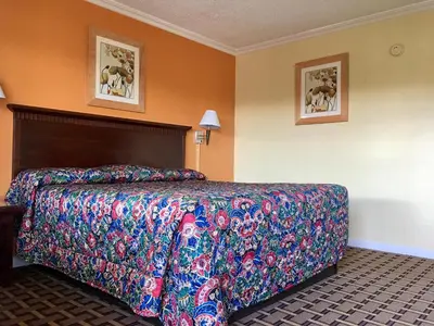 a bed in a hotel room with a colorful bedspread at Kings Rest Motel in Lemoore