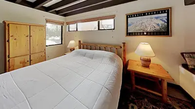 a bedroom with a bed and a table with a lamp at Warm and Cozy 4 Bedroom Condo in Mammoth! in Mammoth Lakes