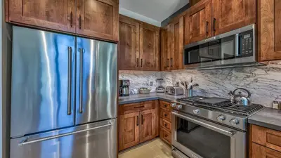 a kitchen with wooden cabinets and stainless steel appliances at Luxury 2Br Residence Steps From Heavenly Village & Gondola Condo in South Lake Tahoe