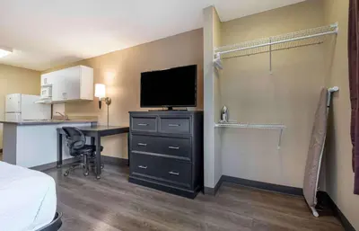 a hotel room with a bed and a desk with a television at Extended Stay America Suites - Sacramento - Roseville in Roseville