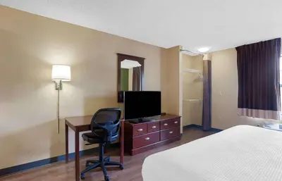 a hotel room with a bed and a desk with a television at Extended Stay America Suites - Sacramento - Roseville in Roseville