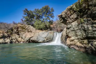 a waterfall on a river next to a rocky cliff at Escape to Yosemite in Groveland