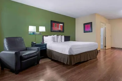 a hotel room with a bed and a chair at Extended Stay America Suites - Sacramento - Arden Way in Sacramento