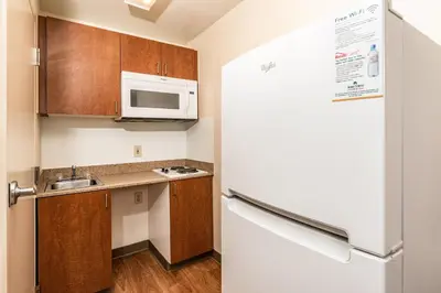 a small kitchen with a refrigerator and a microwave at HomeTowne Studios by Red Roof Fresno - West in Fresno