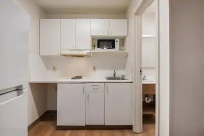 a white kitchen with a sink and a microwave at HomeTowne Studios by Red Roof Fresno - West in Fresno