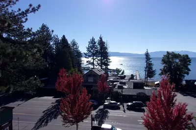 a view of a house with red trees in front of the water at Pepper Tree Inn Tahoe City in Tahoe City