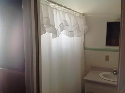 a bathroom with a white shower curtain and a sink at Bridgeport Inn in Bridgeport