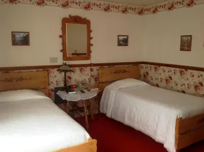 a bedroom with two beds and a mirror and a table at Bridgeport Inn in Bridgeport