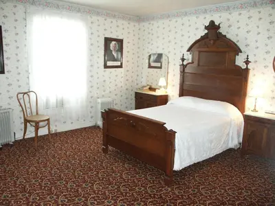 a bedroom with a large bed and a chair at Bridgeport Inn in Bridgeport