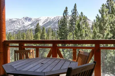 a wooden table and chairs on a porch with mountains at Juniper Crest #25 Condo in Mammoth Lakes