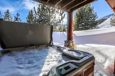 a hot tub sitting in the snow on a porch at Juniper Crest #25 Condo in Mammoth Lakes