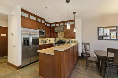 a kitchen with wooden cabinets and a stainless steel refrigerator at Juniper Crest #25 Condo in Mammoth Lakes