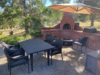 a table and chairs with a brick fireplace and an umbrella at Kin House Guest Suite in Oakhurst
