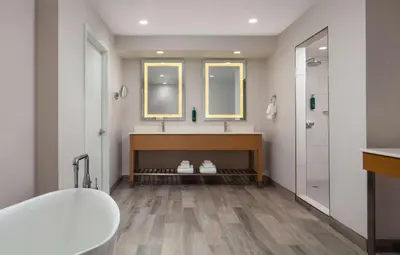 a bathroom with a tub and two sinks and two mirrors at DoubleTree By Hilton Sacramento in Sacramento
