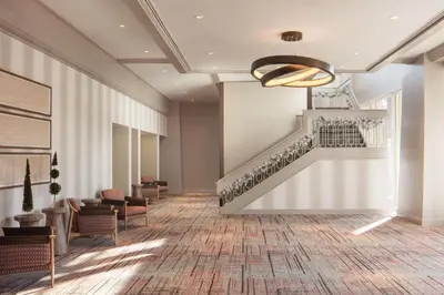 a lobby with a staircase and chairs and a stair case at DoubleTree By Hilton Sacramento in Sacramento