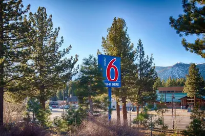a blue and red sign in front of trees at Motel 6-Mammoth Lakes, CA in Mammoth Lakes