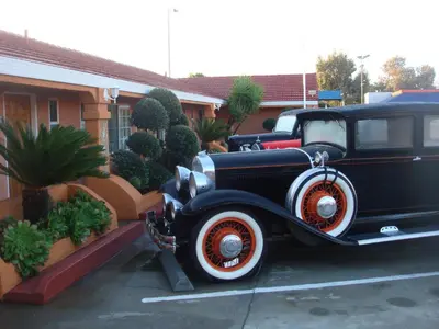 an old black car parked in a parking lot at Economy Inn Los Banos in Los Banos