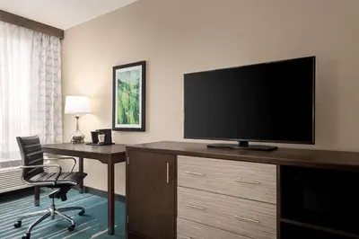 a hotel room with a desk and a flat screen tv at La Quinta by Wyndham Clovis CA in Clovis