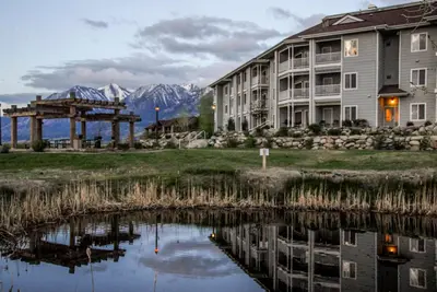 a building next to a lake with mountains in the background at Holiday Inn Club Vacations - David Walley's Resort in Genoa