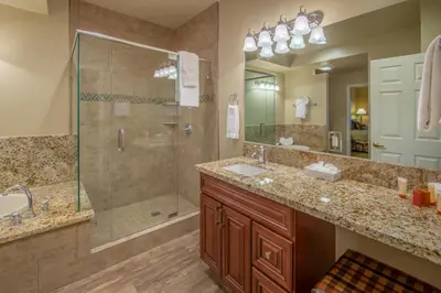 a bathroom with two sinks and a glass shower at Holiday Inn Club Vacations - David Walley's Resort in Genoa