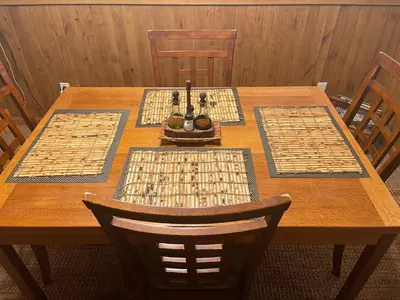 a wooden table with four chairs and a wooden table with a chess at A Lovely Cabin House at Way Woods Retreat with Outdoor Hot Tub! - By Sacred Hub MGMT in Foresthill