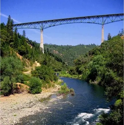 a bridge over a river with a river at A Lovely Cabin House at Way Woods Retreat with Outdoor Hot Tub! - By Sacred Hub MGMT in Foresthill