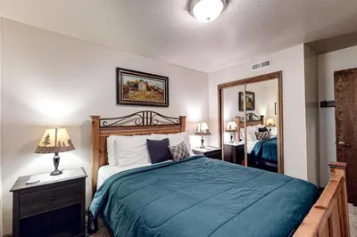 a bedroom with a bed with a blue blanket and a mirror at Cherry Retreat in South Lake Tahoe